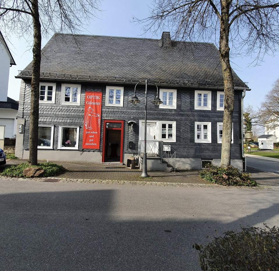 Schiefergedecktes Haus von Optik Günster in Brilon mit rotem Banner am Eingang